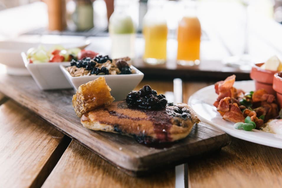 Breakfast on a wooden board with fruit, yoghurt and juice