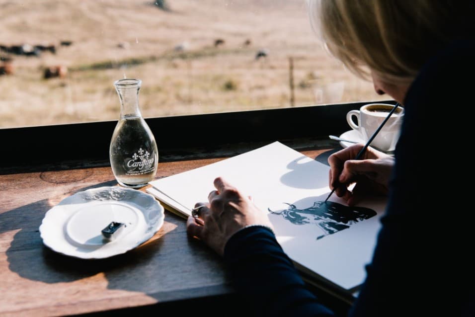 Painting a watercolour at a café window overlooking the hills