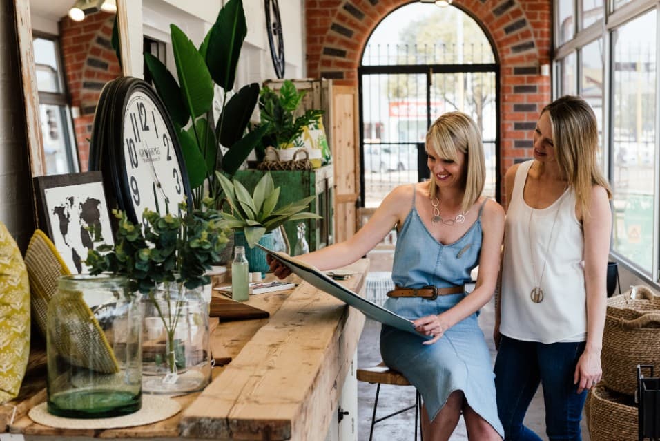 Two women looking at a framed artwork in a shop