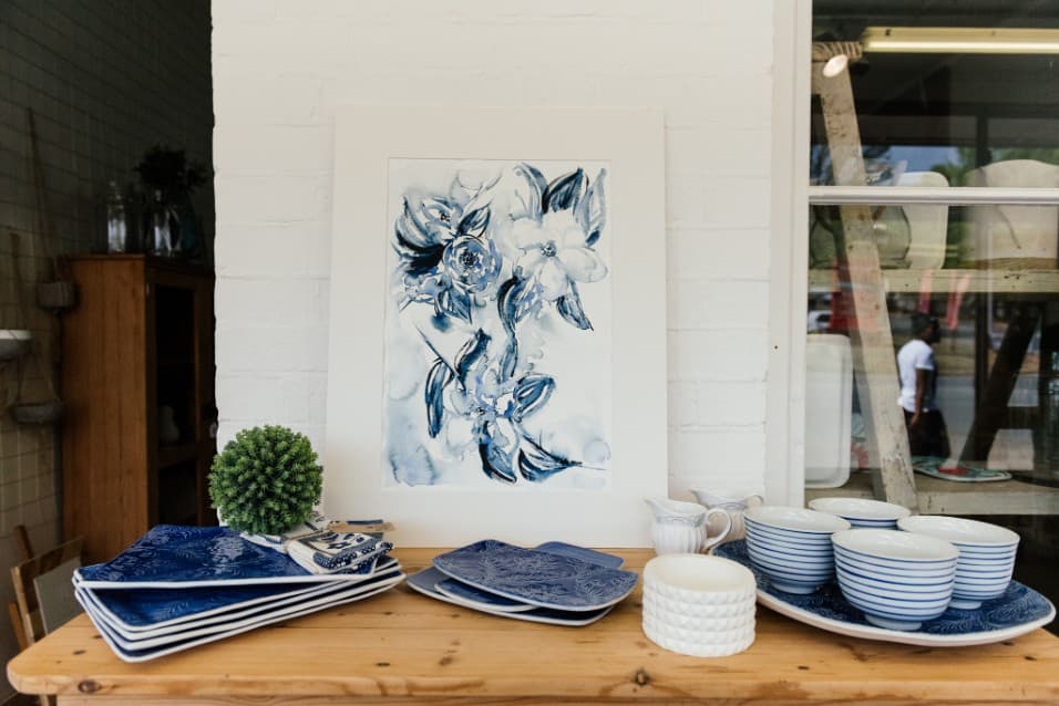 Large blue floral watercolour above stacks of blue and white crockery
