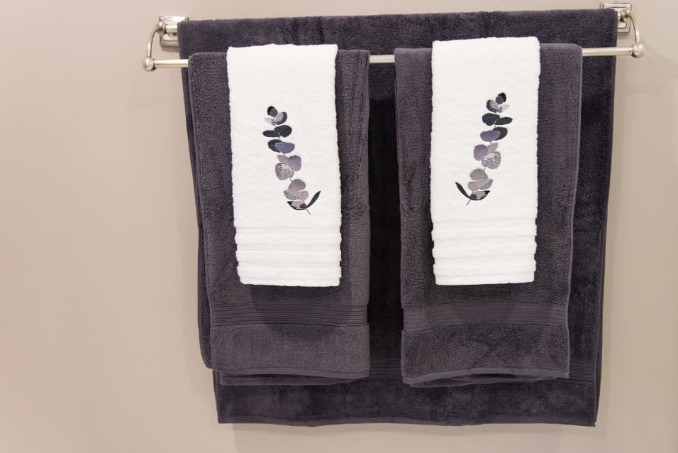 Grey towels with embroidered leaf panels on a towel rail