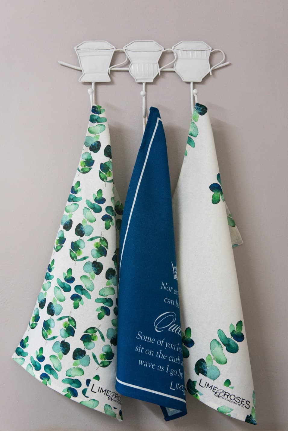 Three printed tea towels hanging on hooks