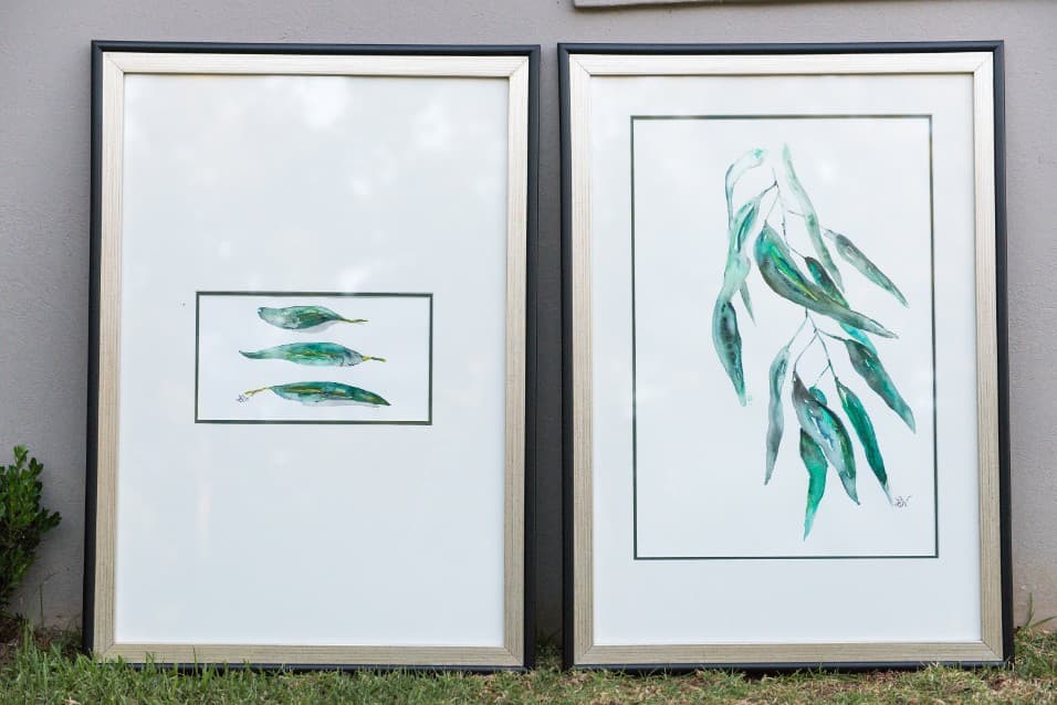 Two framed gum-leaf watercolours leaning against a wall