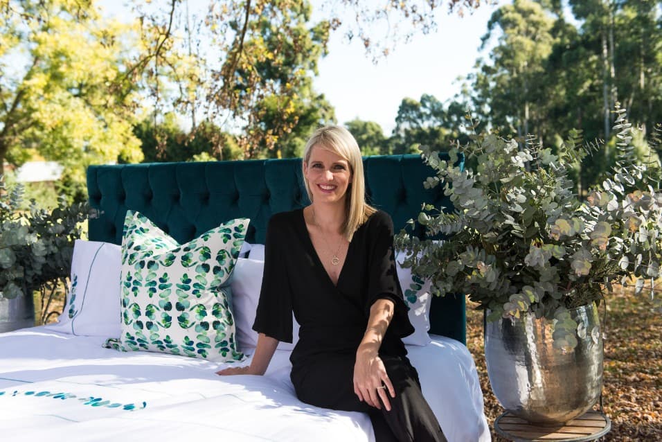 Woman sitting on a bed with eucalyptus-print cushions outdoors