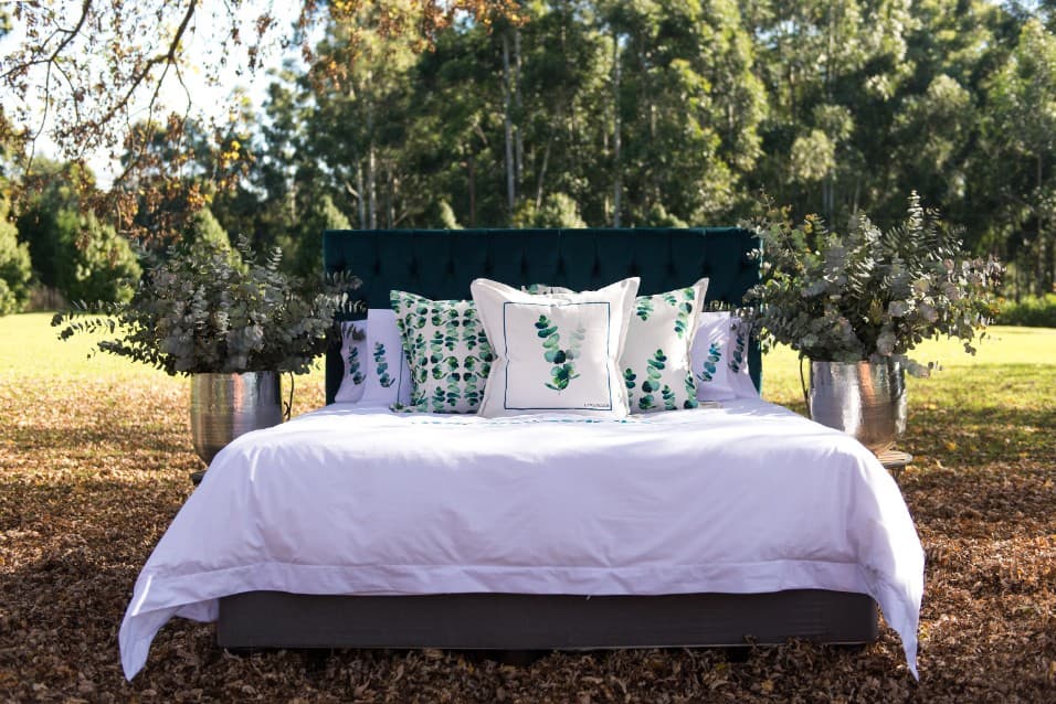 Bed made up with eucalyptus-print linen in a garden