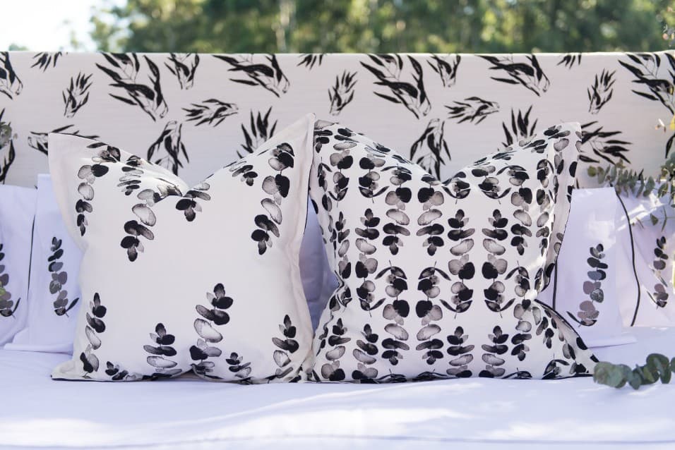 Black and white leaf-print cushions on a bed