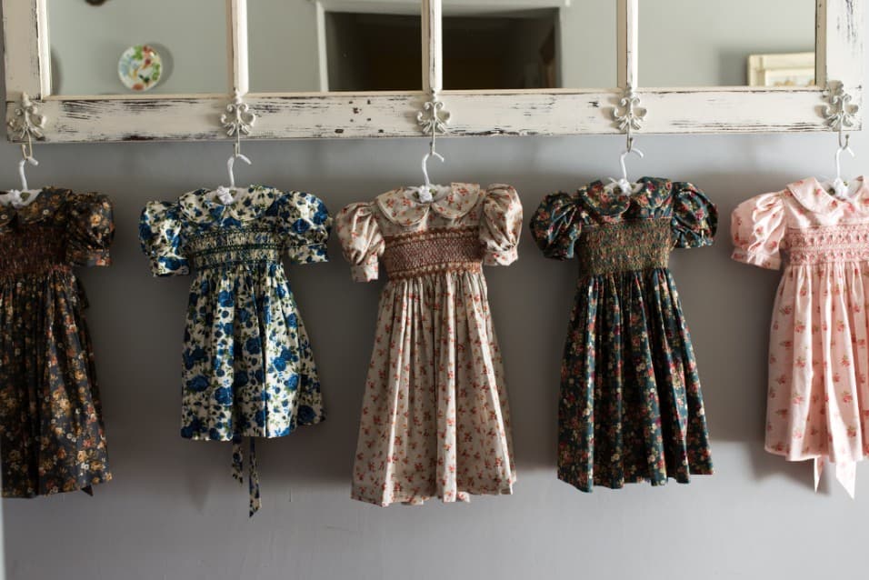 Smocked floral children's dresses hanging in a row