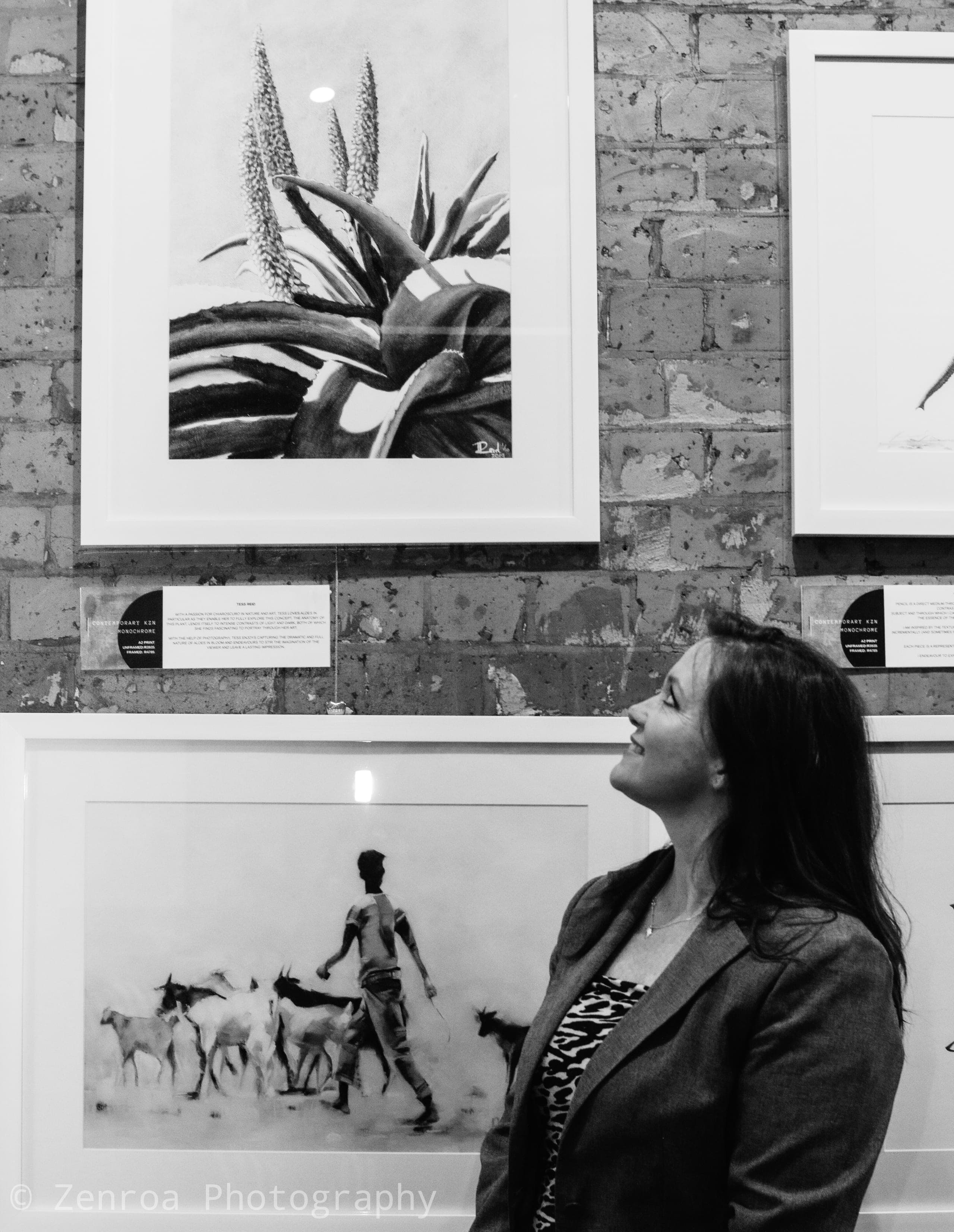 Visitor looking up at framed monochrome artworks