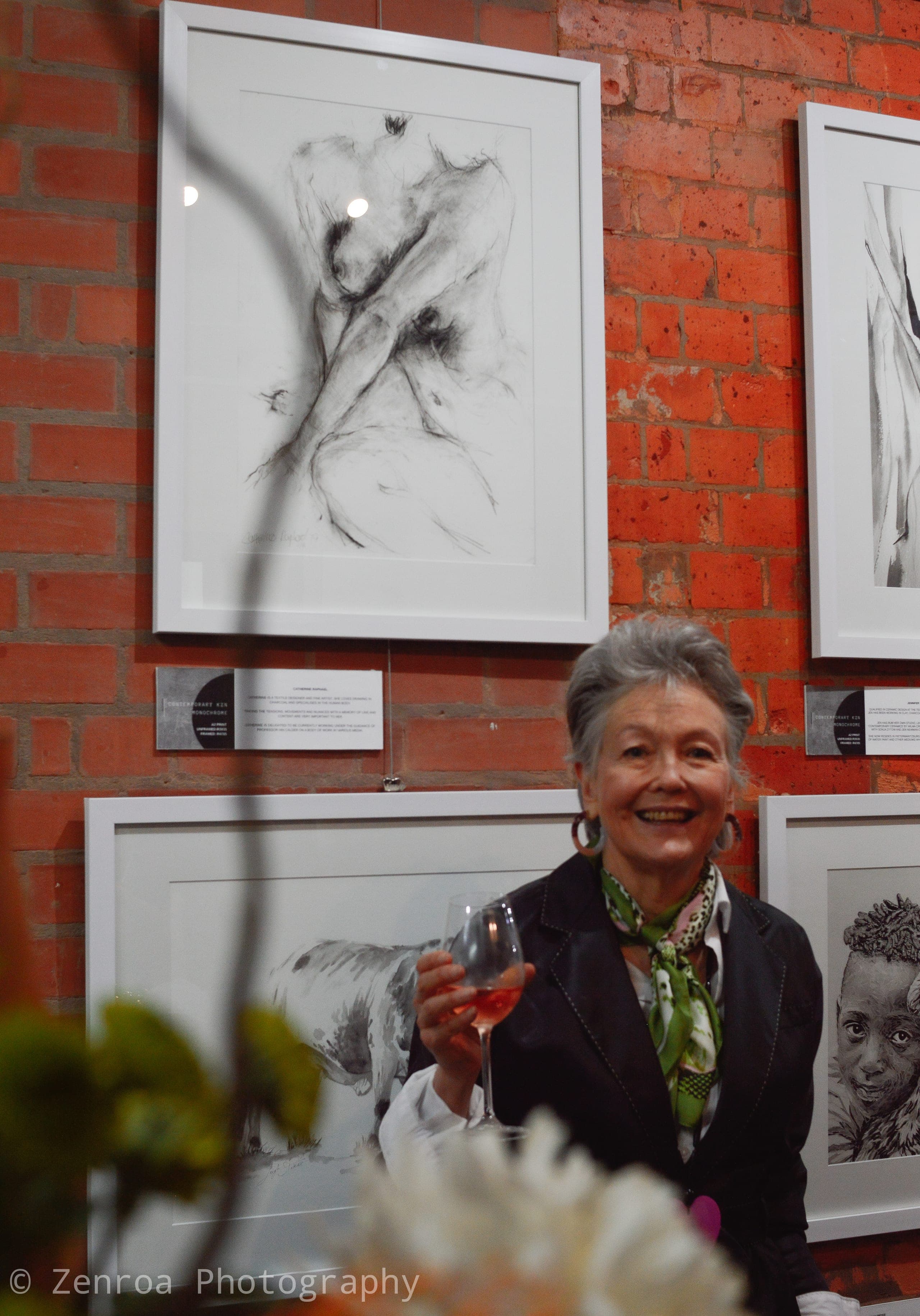 Guest with a glass of wine beside the artworks