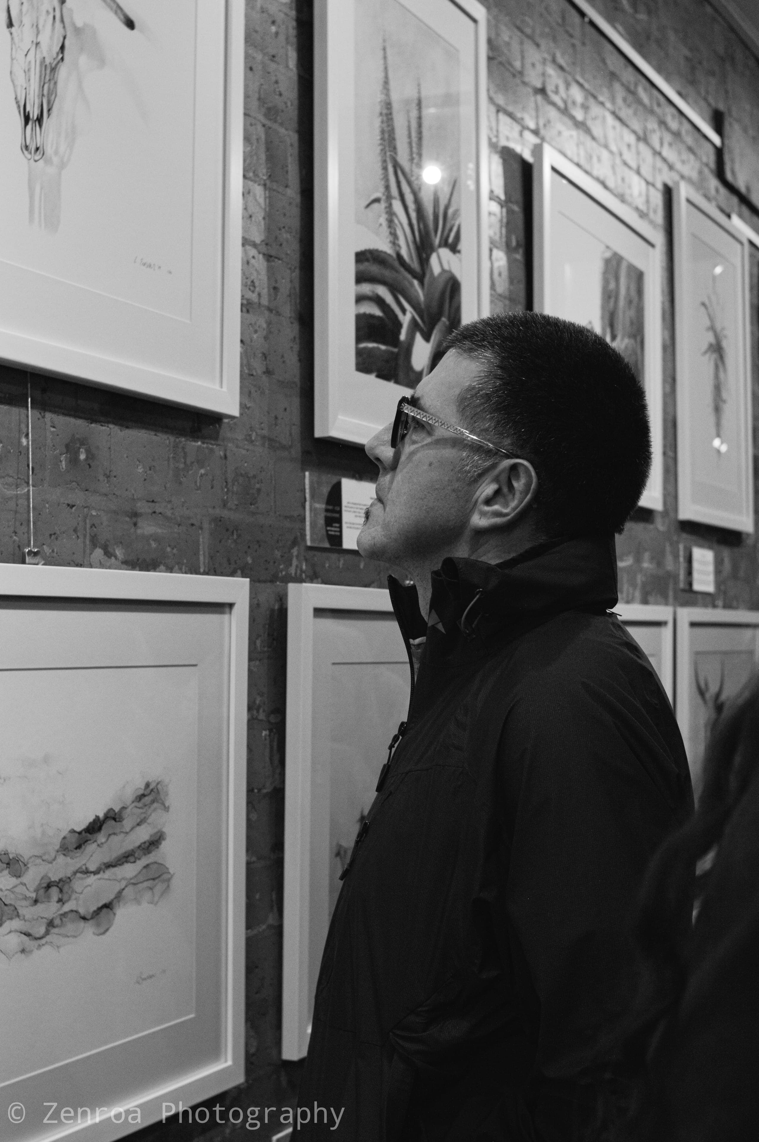 Visitor studying the framed monochrome artworks