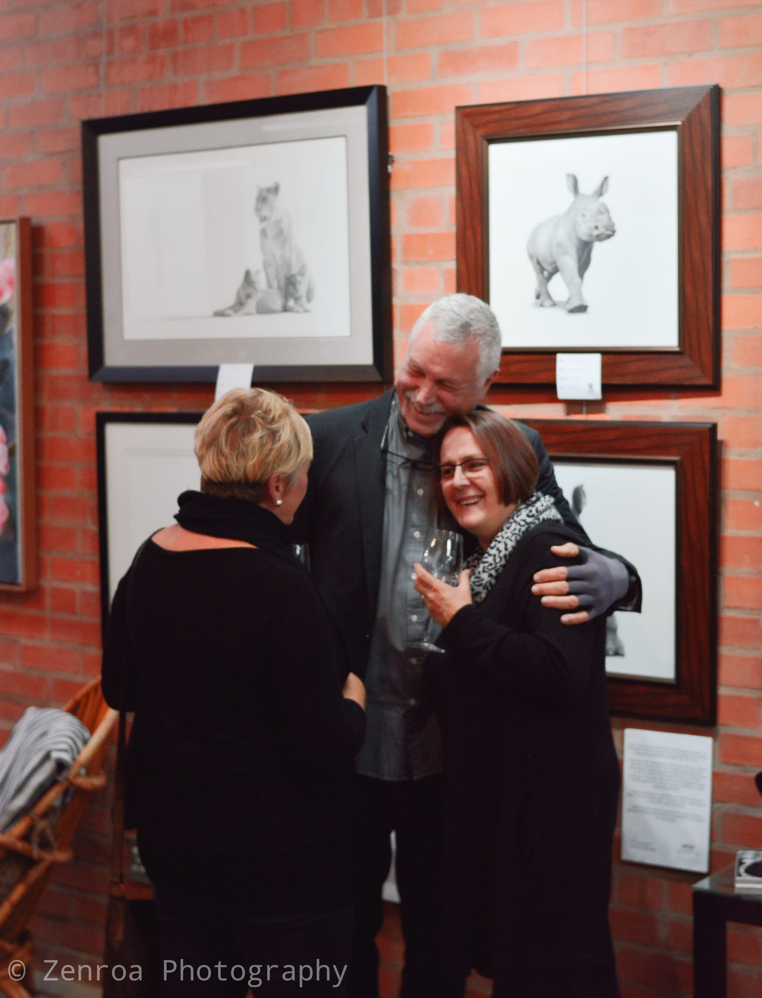 Guests embracing in front of framed artworks