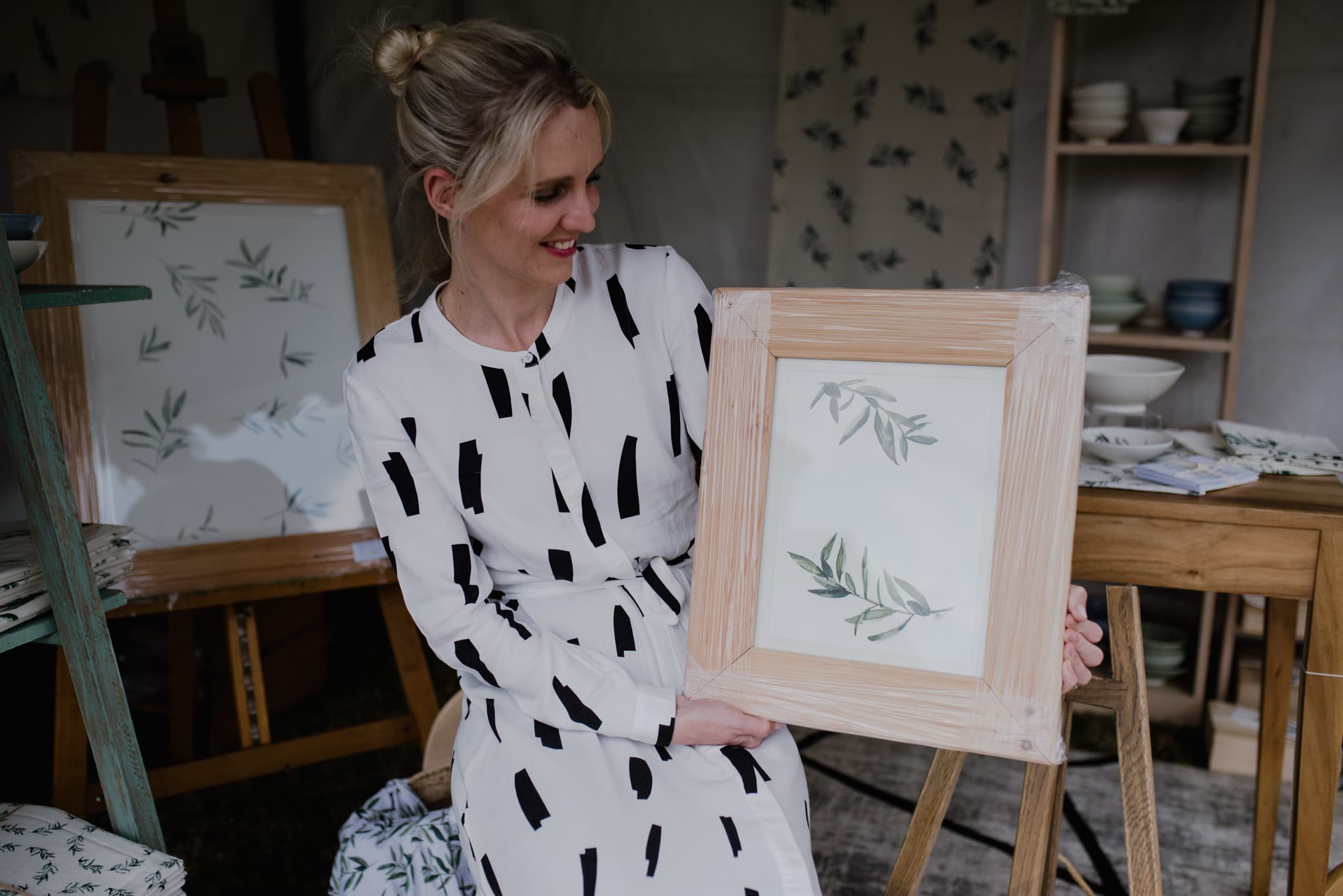 Woman holding a framed olive-branch watercolour